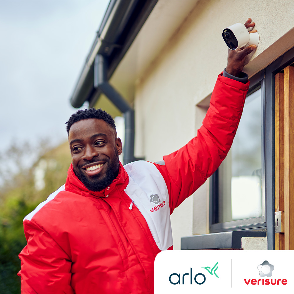 A professional alarm technician wearing a Verisure jacket - Arlo and Verisure Logo are on the lower right