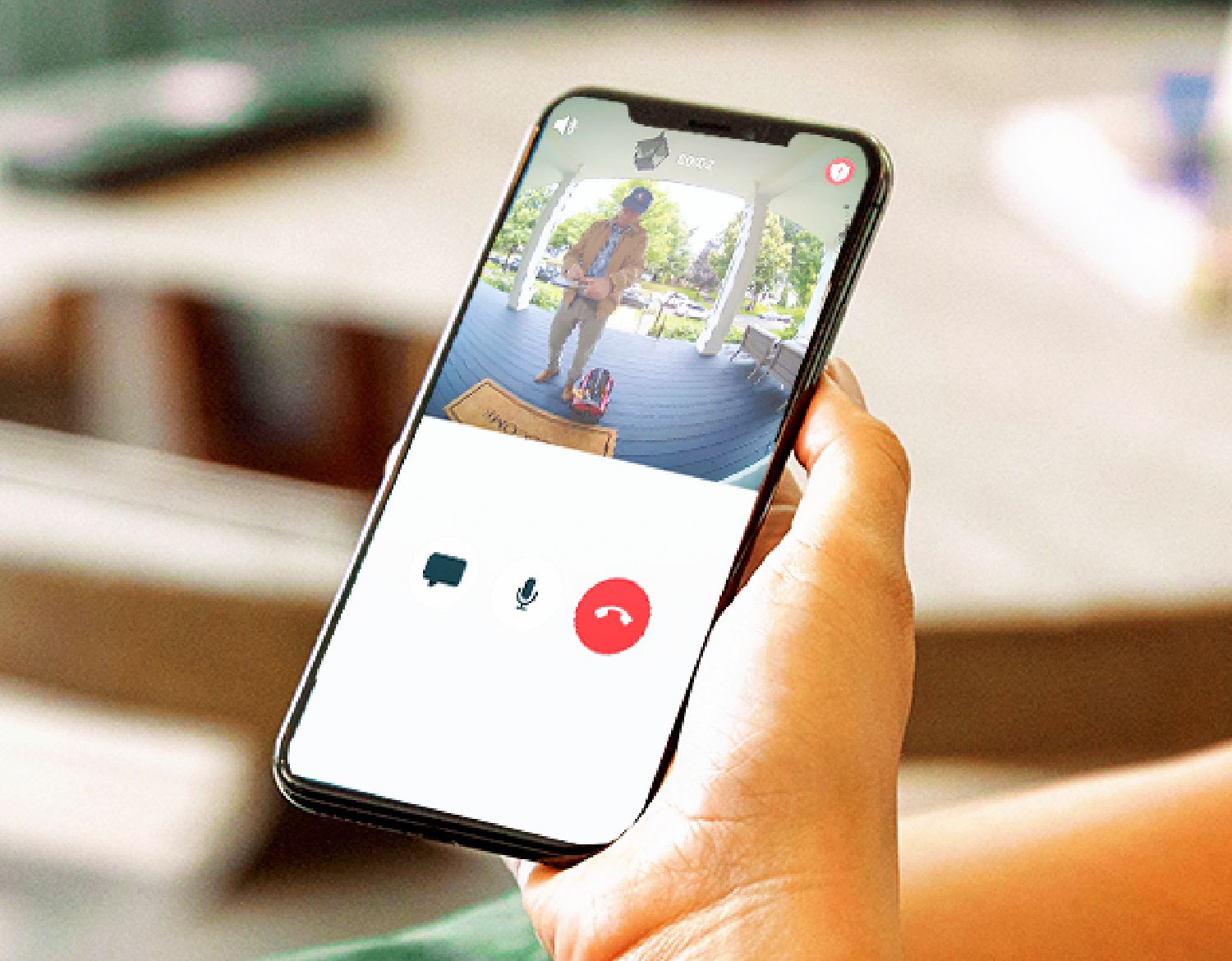 A close up view of a mobile phone screen showing a delivery man at the front door captured by an Arlo Essential XL security camera