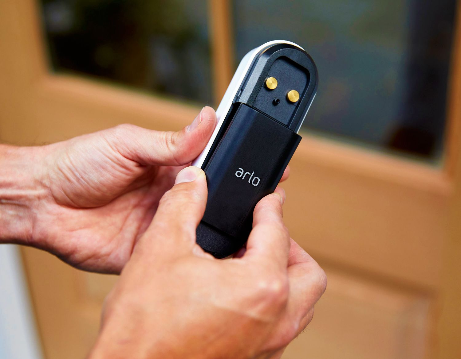 A person inserts a rechargeable battery into an Arlo wire-free video doorbell